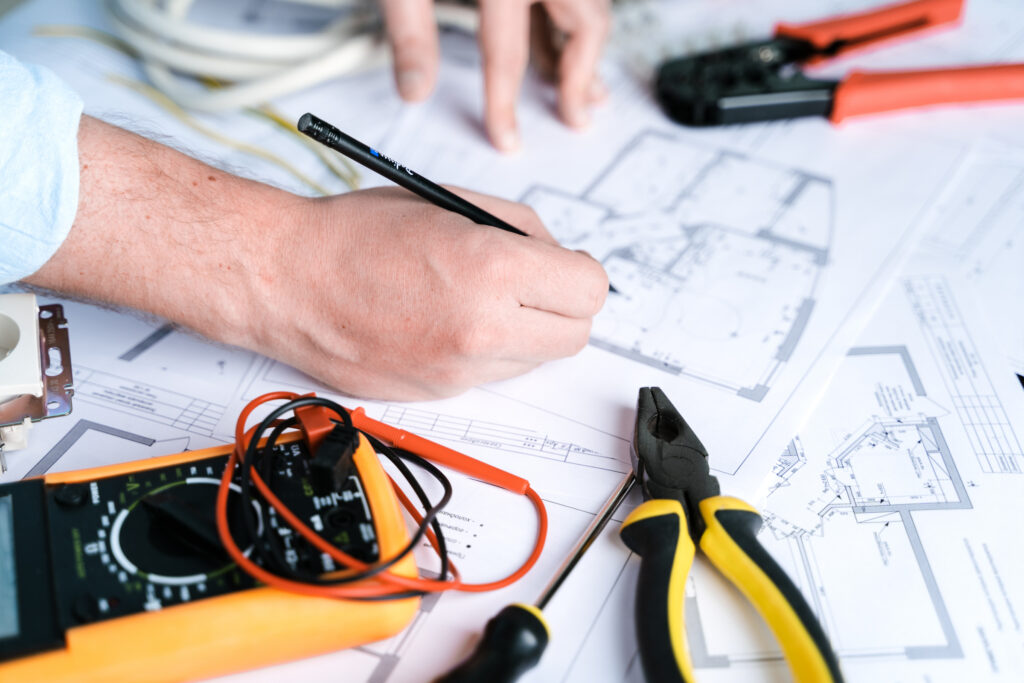 Charlotte residential electrician drawing home electrical design with multimeter and wire cutters nearby