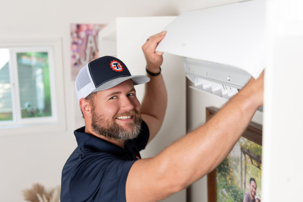 a Travis Crawford service technician performing maintenance on a mini-split HVAC system in Charlotte, NC