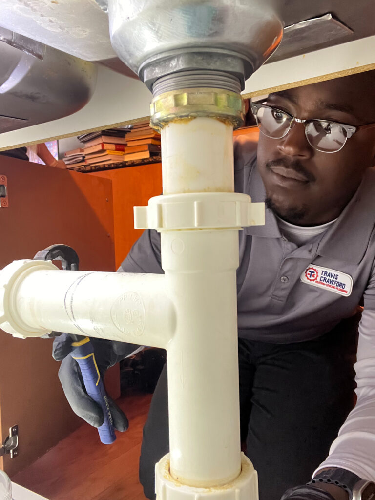 a Travis Crawford plumber performs plumbing maintenance by checking for leaks in a Charlotte, NC home